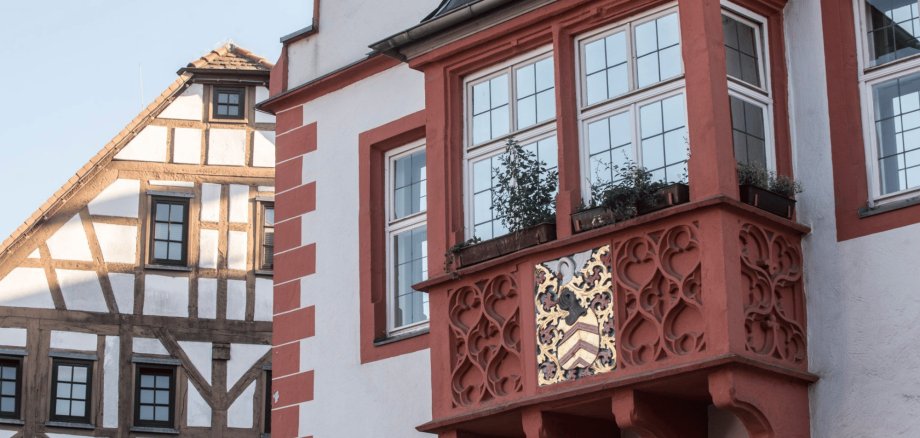 Außenfassade eines alten Hauses mit Balkon und Wappen