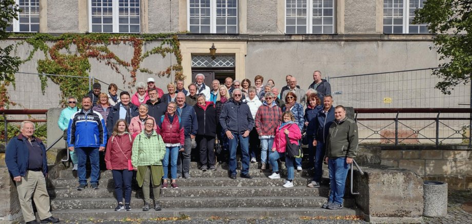 Mehrere Personen stehend auf einer Steintreppe vor einem Haus