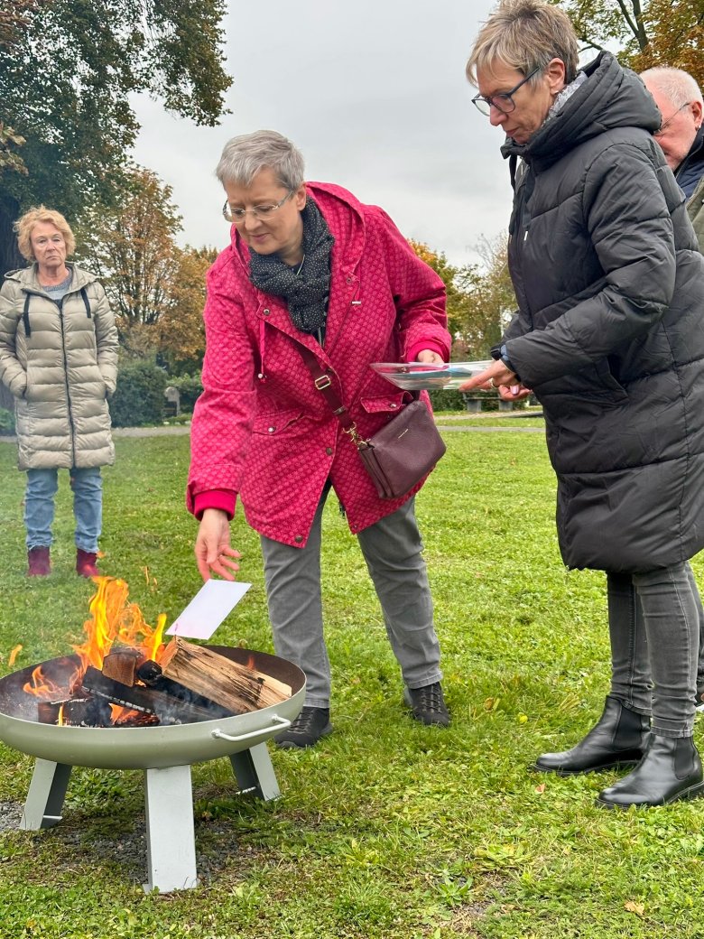 2 Frauen vor einer Feuerschale mit einem Brief in der Hand