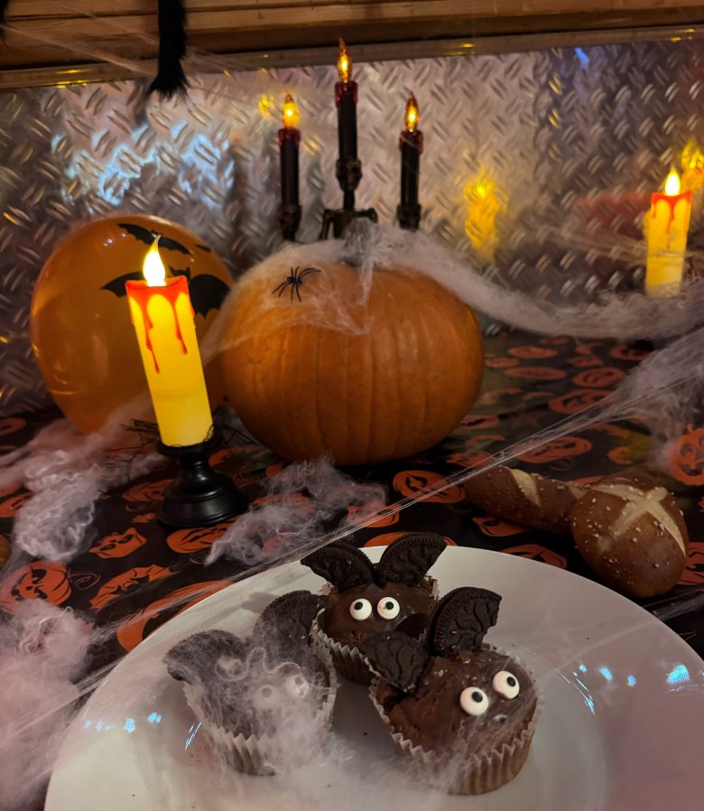 Halloween-Tafel mit Muffins und einem Kürbis und einer LED-Kerze