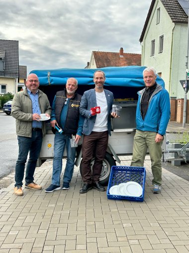 Mehrere Männer stehend vor einem Anhänger mit Geschirr